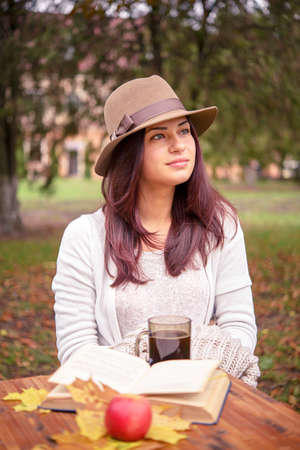 beautiful girl in the hat at the table with bookの写真素材