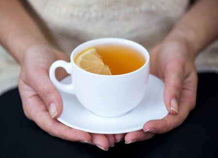 cup of tea with lemon close in two handsの写真素材