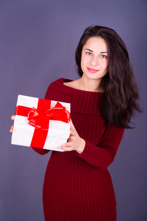 smiling pretty girl in a red dress with a giftの写真素材