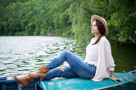 relaxed pretty girl sitting in a boat on a lakeの写真素材