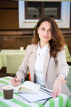Young business girl invites to a conversation in the summer cafeの写真素材