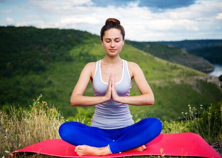 Young girl is practicing meditation in front of the horizonの写真素材