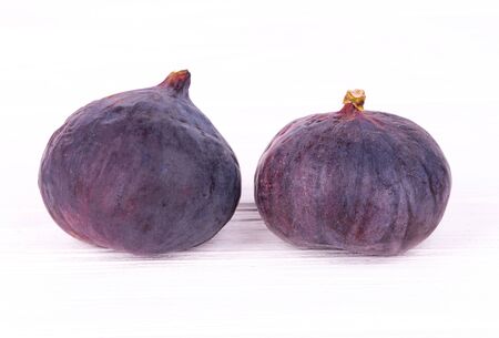 Two ripe figs close-up on white wooden tableの写真素材