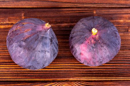 Two ripe figs on wooden surface top viewの写真素材