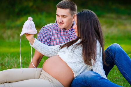 Happy and young pregnant couple viewing baby things in natureの写真素材