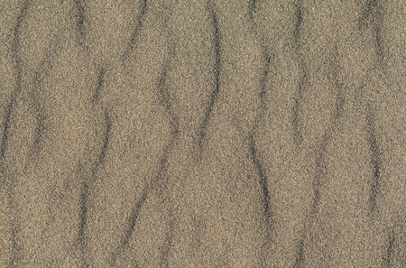 Closeup of volcanic gray sand pattern of a beach in the summerの写真素材