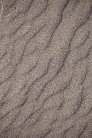 Closeup of volcanic sand pattern of a beach in the summer - with red tintの写真素材