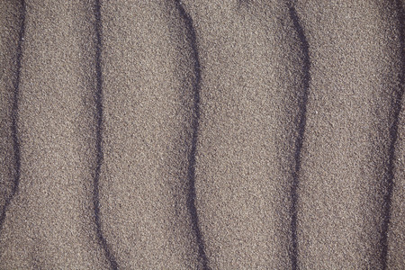 Closeup of volcanic sand pattern of a beach in the summer - with red tintの写真素材