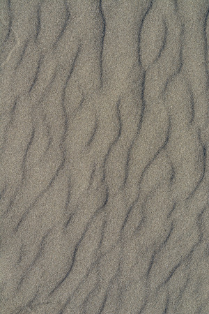 Closeup of volcanic gray sand pattern of a beach in the summerの写真素材