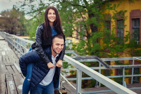 Beautiful young couple in love on a date outdoors on modern urban background. Smiling and hugging. Bearded handsome rustic man and brunette pretty woman in casual dress.の写真素材