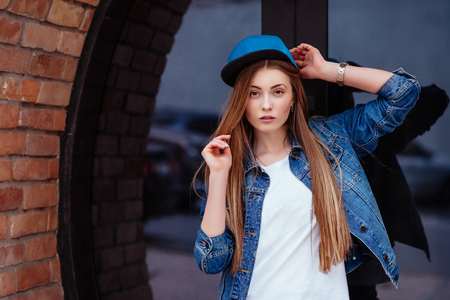 Young sexy glamour woman wearing jeans jacket and baseball cap. Lifestyle city portrait in swag style.の写真素材