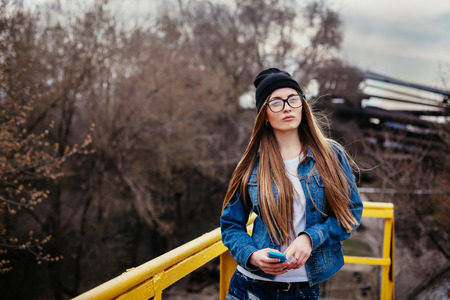 Outdoor fashion lifestyle portrait of pretty young girl, wearing in hipster swag grunge style urban background.の写真素材