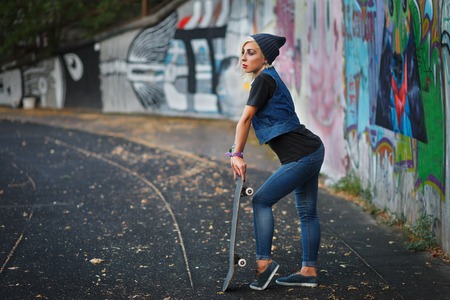 Outdoor lifestyle portrait of pretty young girl, wearing in hipster swag grunge style on urban background with graffiti. Retro vintage toned image, film simulation.の写真素材