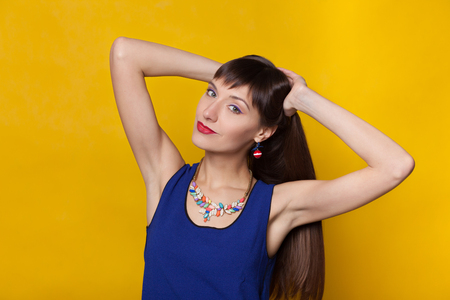Closeup fashion portrait of beautiful model woman with bright makeup. Beauty face. Isolated on orange or yellow colorful background in studio.の写真素材