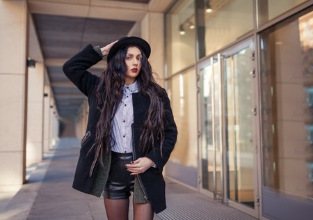 Outdoor lifestyle portrait of pretty young girl, wearing hipster swag grunge style on urban background. Wearing hat and jeans with backpack. Spring fashion woman.の写真素材