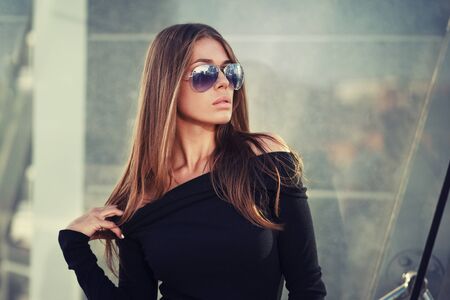Beautiful brunette young woman in nice black dress, sunglasses. Fashion Photoの写真素材