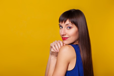 Closeup fashion portrait of beautiful model woman with bright makeup. Beauty face. Orange colorful background in studio.の写真素材