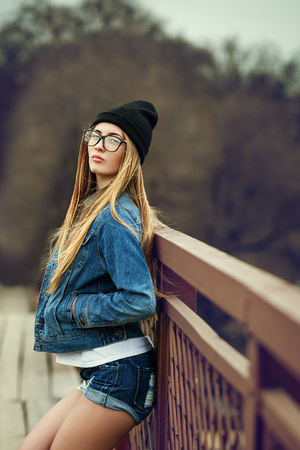 Outdoor lifestyle portrait of pretty young girl, wearing in hipster swag grunge style urban background. Retro vintage toned image, film simulation.の写真素材