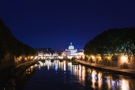 Cityscape romantic night view of Roma. Panorama with Saint Peter's basilica and Saint Angelo castle and bridge. Famous tourist destination with Tiber. Travel illuminated landscape in Italy, Europe.の写真素材