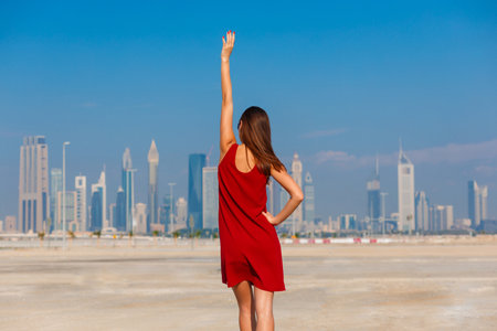 Tourist woman enjoying view of Dubai with palms and skyscrapers from the desert. Sunny summer day in Dubai desert. Dubai is famous tourist destination in UAE. Ideal place for luxury travel and restの写真素材
