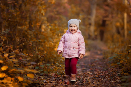 Adorable little girl having fun in the autumn park. Outdoor portraitの写真素材