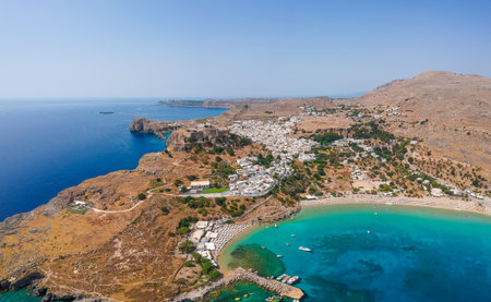 Aerial birds eye view drone photo of village Lindos, Rhodes island, Dodecanese, Greece. Sunset panorama with castle, Mediterranean sea coast. Famous tourist destination in South Europe.の写真素材
