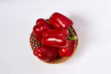 Several large red beautiful pepper lie in a wattled plateの写真素材