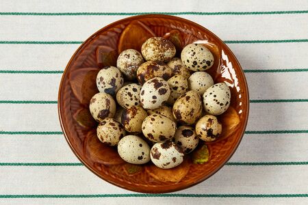 Several small quail eggs lie in a ceramic plateの写真素材