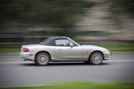 Cabriolet car racing on road. Convertible with a closed top rushing down the road. Everything is blurredの写真素材