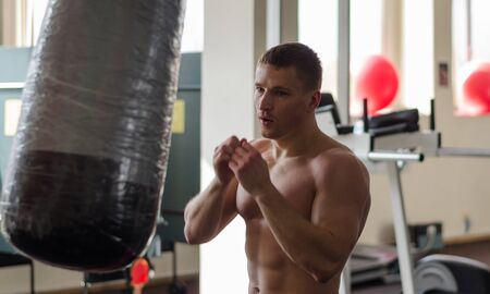 Young athlete in motion with blurred hands on training with a boxing bag gymの写真素材