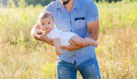 A young Dad with a baby in her arms. Walk autumn evening outdoors.
