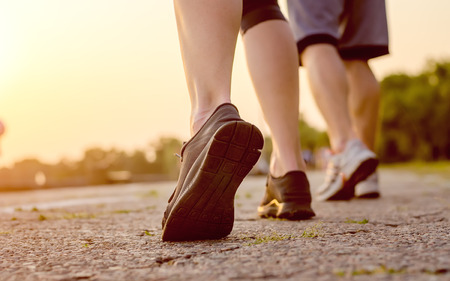 Close-up of athletes foot while jogging outdoors. Soles of shoes, men and women at sunset.