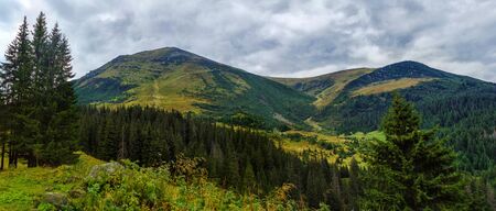 Beautiful mountain wide panorama with views of the high peak with the clouds in Carpathian mountain...
