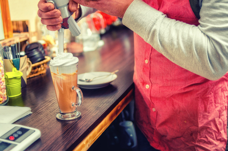Barista pours gentle cream into the cup for the cappuccino. Close up bright background.の写真素材
