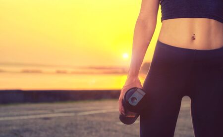 Close up portrait of a sports girl  holding a shaker with protein  and standing of the road at...