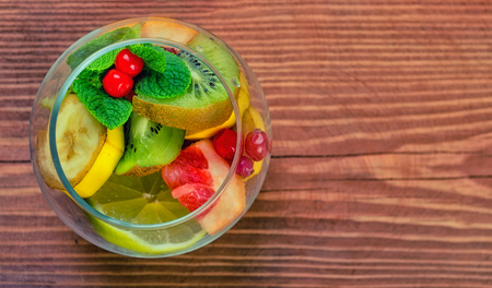 Delicious dessert with mint, cranberry and fresh fruit in a glass jar on wooden background. Top of view.の写真素材