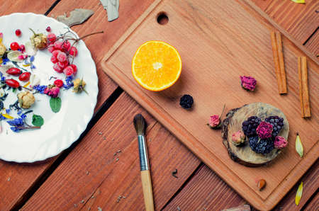 Art conceptual photo with flowers, brush, fruit and spices  on a plate on a wooden background.の写真素材