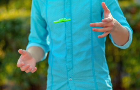Teenager hand throws  antistress popular gadget fidget spinner. Man on the azure shirt and blue...