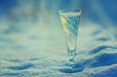 Glass of  champagne with ice pattern on a winter snow  with blue vintage backgroung. Shallow DOF. Christmas conceptual photo.の写真素材