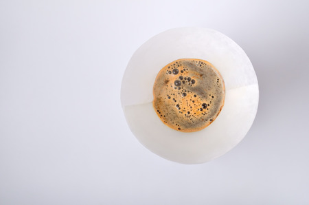 The paper filter with mix of the hot water and coffee powder  in the vintage drink maker isolated on the blank background. Top of view.  の写真素材