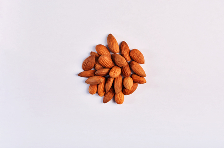 A handful of dry raw almond nuts on a studio white background. Food vegetarian composition top of the view.の写真素材