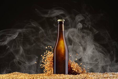Drink mockup series. Brown beer bottle with reflections on a smoke black studio background with scattering wheat corns. Template ready to use on your showcase.の写真素材