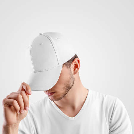 Mockup of a white baseball cap on a guy, straightening visor, side view, textile hat for presentation of design, pattern. Headdress template for sun protection, uniform, isolated on background.の写真素材