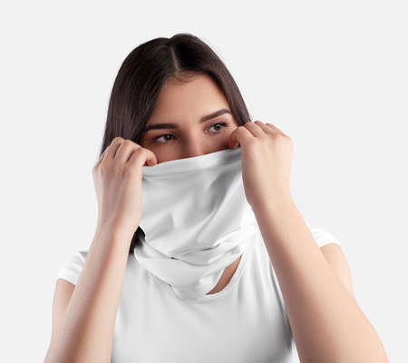 Mockup white texture buff on a young girl with dark hair straightening a blank half mask, for a design presentation. Cloth kerchief template covering face isolated on background for advertisingの写真素材
