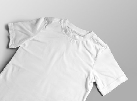 Mockup of white children's t-shirt close-up, wear with a round neck, label, close-up, diagonal presentation, front view. Product photography for design. Kids apparel template isolated on backgroundの写真素材