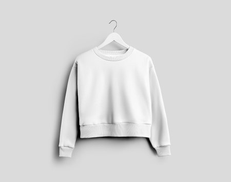 Mockup of white women's crop sweatshirt on hanger, item isolated on background, front view. Product photography for advertising. Template female clothes with a round neck, cuffs, for design, brandingの写真素材