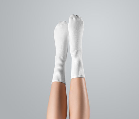 Template of white high socks on women's feet, with stretched toes, presentation legs up, front, isolated on background. Mockup of gaiters on feet with long elastic band, for design, brandingの写真素材