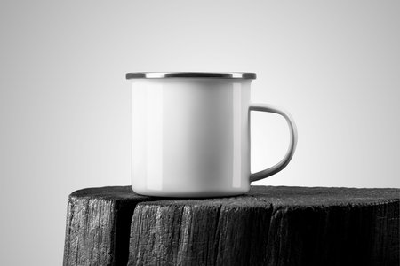 White enamel mug mockup on burnt wood, iron cup with silver rim on cup, handle, place for design, print, pattern, branding. Travel mug template on board, stylish composition, isolated on backgroundの写真素材
