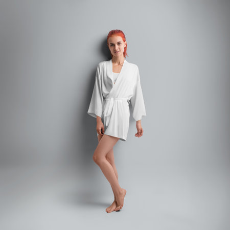 Mockup of a short silk robe with a belt at the waist, on a red-haired girl, full-length front, isolated on background. Female kimono template for design, branding. Product photography for advertisingの写真素材