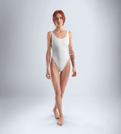 Mockup of a white sports swimsuit one piece on a slender redheaded girl in full height, front view, for design, pattern. Template of a fashionable female monokini for swimming, isolated on backgroundの写真素材
